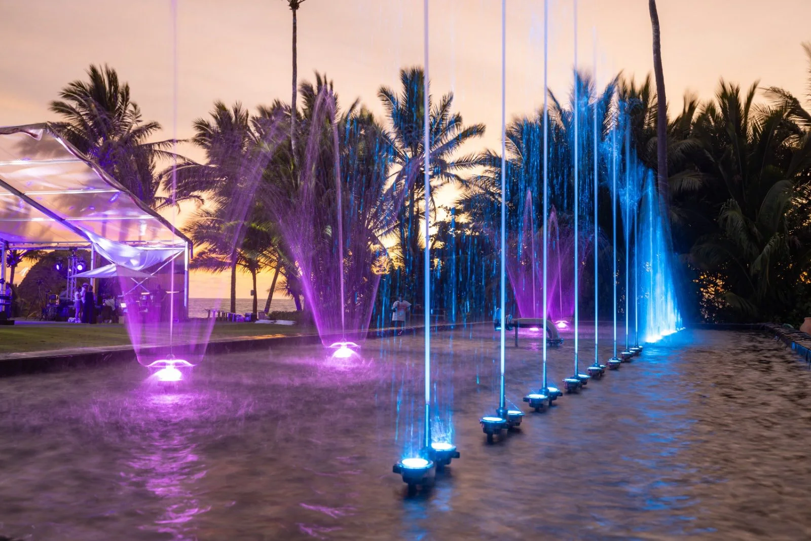 Fuente coreografiada con chorros iluminados azules y violetas en un evento