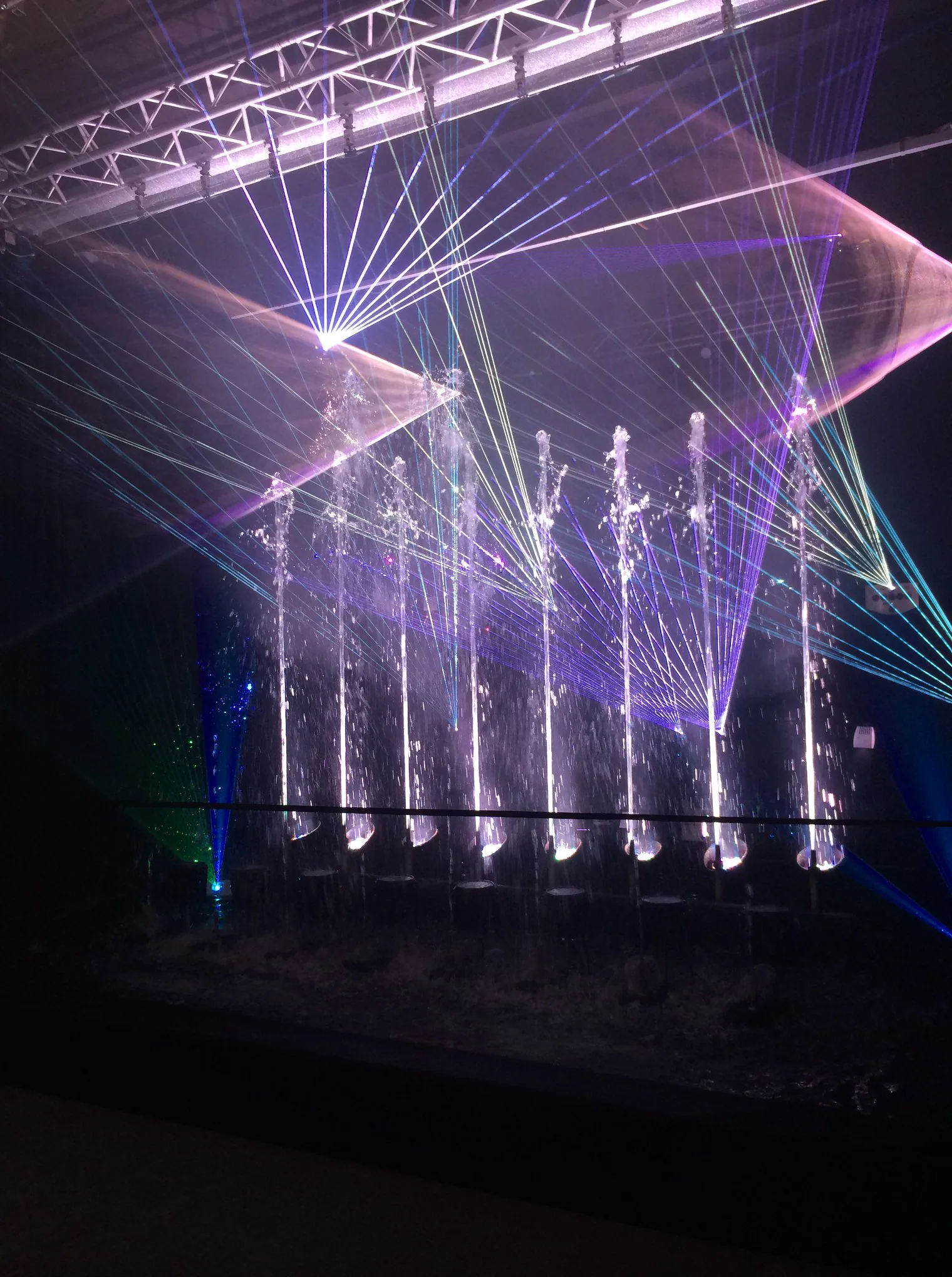 Fuente musical con láser y efectos de agua durante un espectáculo nocturno