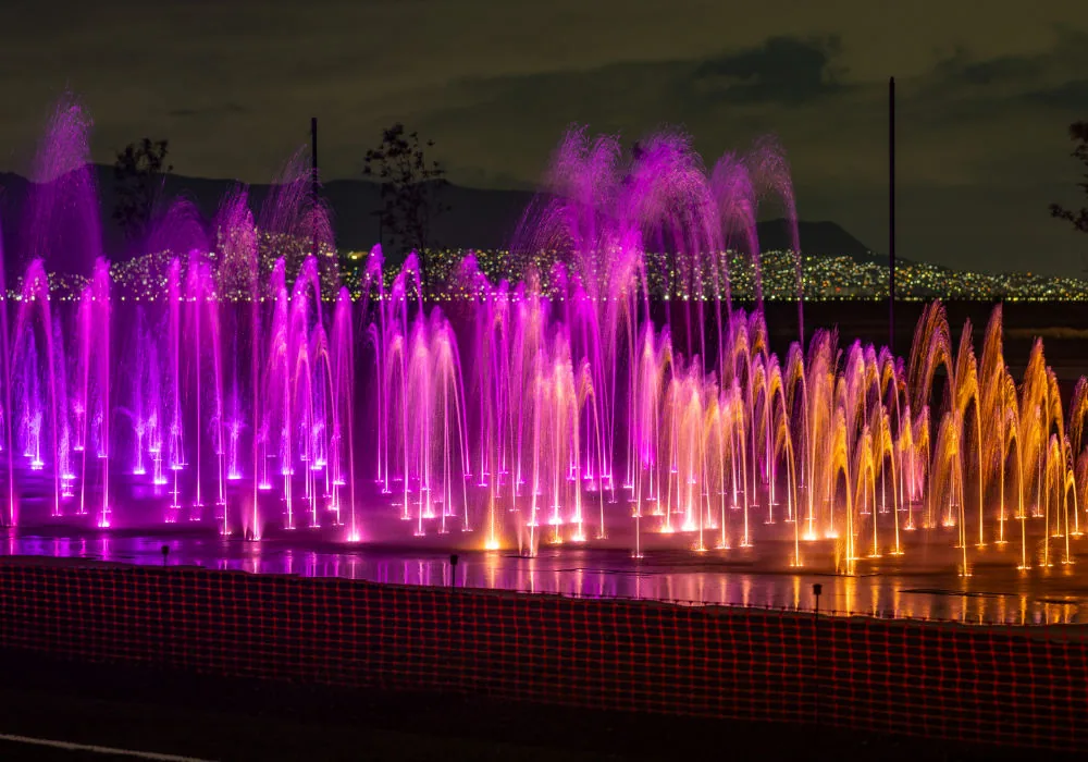 Fuente bailarina de piso con chorros iluminados en tonos magenta y ámbar