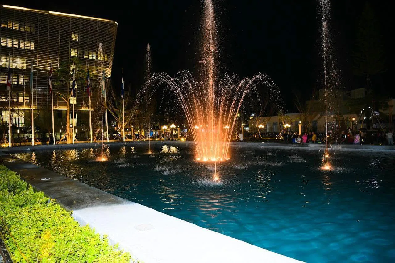 Fuente musical nocturna en El Salvador con iluminación cálida y edificio histórico
